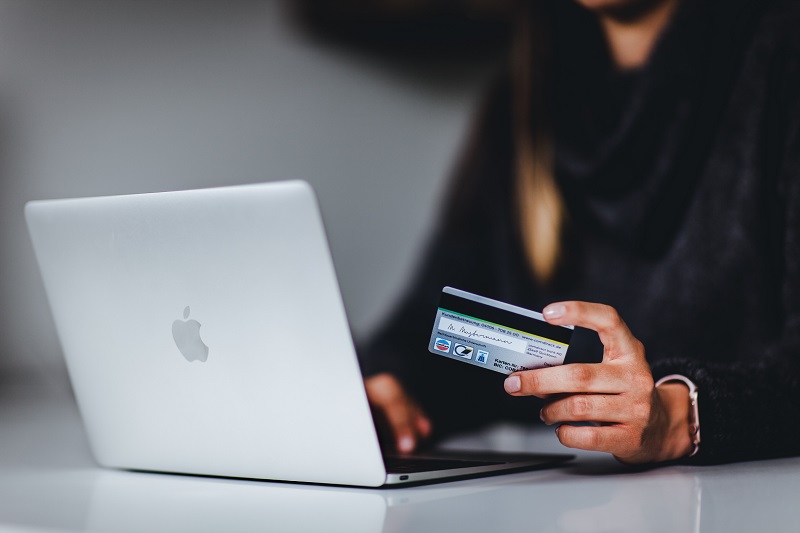woman-holding-credit-card-in-front-of-laptop