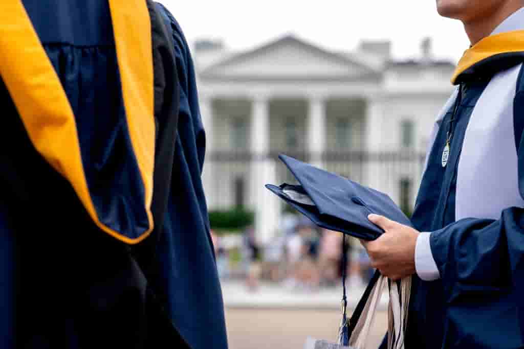 Students from George Washington University wear their graduation gowns outside of the White House in Washington, DC, on May 18, 2022. - US Senator Raphael Warnock (D-GA) is expected to meet with President Biden to push for student loan forgiveness. (Photo by Stefani Reynolds / AFP) (Photo by STEFANI REYNOLDS/AFP via Getty Images)